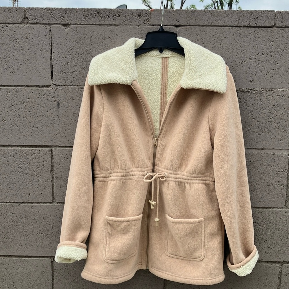 Tan faux Sherpa lined jacket.  Ties at waist. Zips up front. Pockets too.